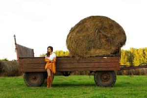 jeune femme et chariot avec des meules de foin dans le village photo