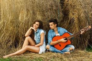 jeune couple heureux dans le village parmi les meules de foin. photo