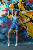 fille en salopette en jean posant contre un mur avec des graffitis photo