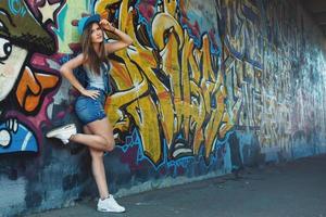 fille en salopette en jean posant contre un mur avec des graffitis photo