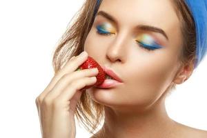 femme avec du maquillage coloré mange des fraises photo