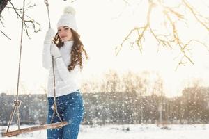 Happy girl on rope swing au jour d'hiver ensoleillé photo