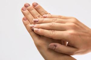 mains féminines avec des ongles sales sur fond gris photo