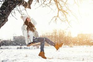 Happy girl on rope swing au jour d'hiver ensoleillé photo