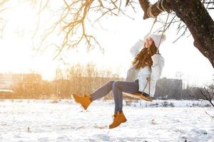 Happy girl on rope swing au jour d'hiver ensoleillé photo