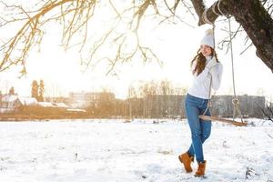 Happy girl on rope swing au jour d'hiver ensoleillé photo