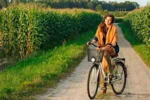 femme fait du vélo sur la route de campagne dans le champ de maïs photo