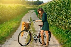 femme fait du vélo sur la route de campagne dans le champ de maïs photo