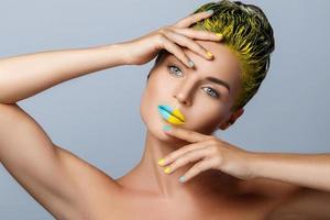 belle femme aux cheveux jaunes et aux ongles et aux lèvres colorés photo