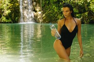 femme avec une bouteille d'eau dans l'oasis de la jungle photo