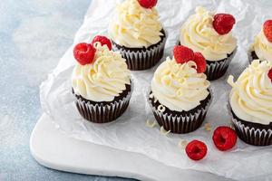 cupcakes au chocolat avec glaçage au chocolat blanc et framboises photo