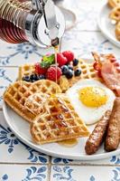 table de petit déjeuner avec des gaufres. œuf au plat, bacon et saucisse photo