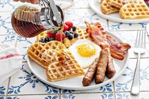 table de petit déjeuner avec des gaufres. œuf au plat, bacon et saucisse photo