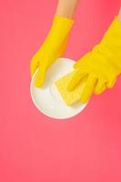 concept de vaisselle, mains dans des gants en caoutchouc pour tenir une éponge jaune et laver la vaisselle photo