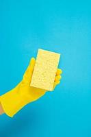 concept de nettoyage, main dans des gants en caoutchouc et tenant une éponge jaune pour laver la vaisselle dans la cuisine photo