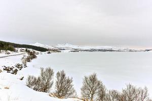 lac enneigé ostadvatnet dans les îles lofoten, norvège en hiver. photo