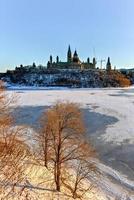 la colline du parlement et la chambre du parlement canadien à ottawa, canada, de l'autre côté de la rivière gelée des ottawa pendant l'hiver. photo