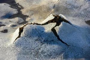 roche se fissurant à travers la glace à boosen dans les îles lofoten, norvège en hiver. photo