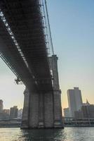 pont de brooklyn contre l'horizon de new york au coucher du soleil photo