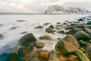 vagues qui coulent sur la plage d'utakleiv, îles lofoten, norvège en hiver. photo