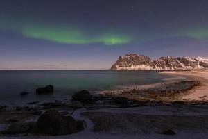 aurores boréales sur la mer à la plage d'utakleiv, îles lofoten, norvège en hiver. photo