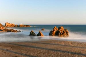 vue imprenable sur une longue exposition de vagues lisses se brisant sur des formations rocheuses au coucher du soleil, point de sequit, plage d'état de leo carrillo, malibu, californie photo