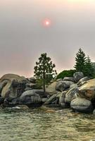 crique secrète le long du lac tahoe au nevada avec un ciel brumeux en raison des incendies de forêt à proximité en californie. photo