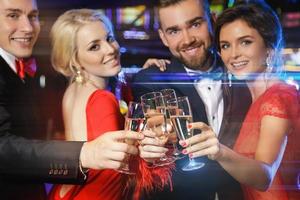 groupe de gens heureux buvant du vin mousseux au casino photo