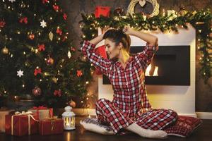 femme heureuse assise à côté de la cheminée dans les décorations de noël photo