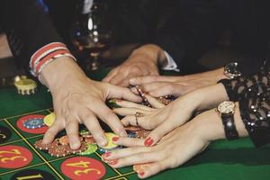 les mains et les jetons de casino de différentes personnes sur la table photo