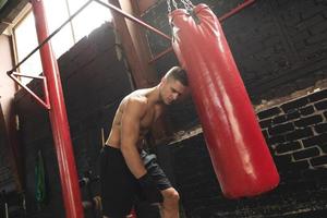 le combattant est très fatigué pendant son entraînement avec un sac de boxe photo