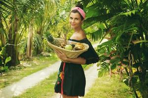 heureuse jeune femme avec un panier plein de fruits exotiques photo