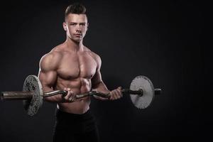 jeune homme bodybuilder avec haltères en studio photo