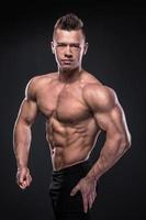 jeune bodybuilder montre ses muscles en studio photo