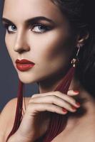 superbe femme avec un beau maquillage portant de longues boucles d'oreilles rouges photo