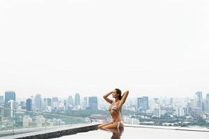 femme se reposant sur une piscine sur le toit avec une belle vue sur la ville photo