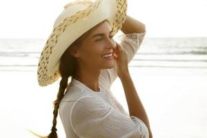 portrait de belle jeune femme avec un chapeau à larges bords sur la plage photo