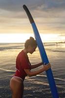 femme fatiguée après une session de surf intense sur la plage au coucher du soleil photo