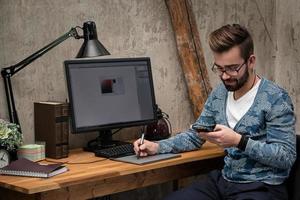 jeune et beau graphiste travaillant sur son lieu de travail photo