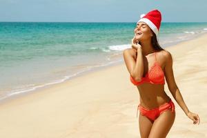 femme portant un bikini et un chapeau de noël sur la plage. vacances d'hiver dans les pays chauds. photo