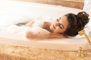 femme heureuse et belle prend un bain avec une mousse photo