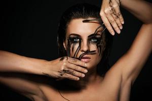 femme avec des taches de maquillage sur son visage et des pinceaux de mascara cassés photo