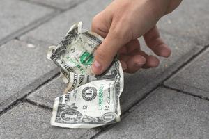 pauvre femme cueillant un billet d'un dollar vieux et froissé photo