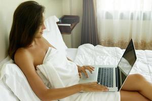 femme allongée sur le lit et utilisant un ordinateur portable photo