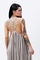 femme avec des tatouages portant une belle robe en studio photo