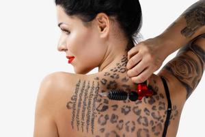 jeune femme tatoueuse avec une machine à tatouer à la main photo