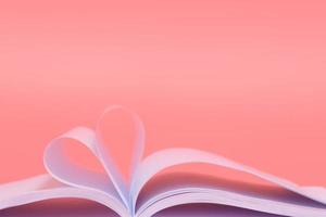 feuilles de livre en forme de coeur isolé sur fond rose photo