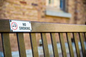 aucun signe de fumer attaché sur le banc de parc en bois. photo