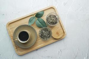 feuilles de thé séchées dans un récipient et tasse de thé sur la table photo