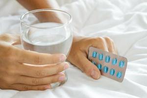 mains féminines avec un verre d'eau et de pilules photo